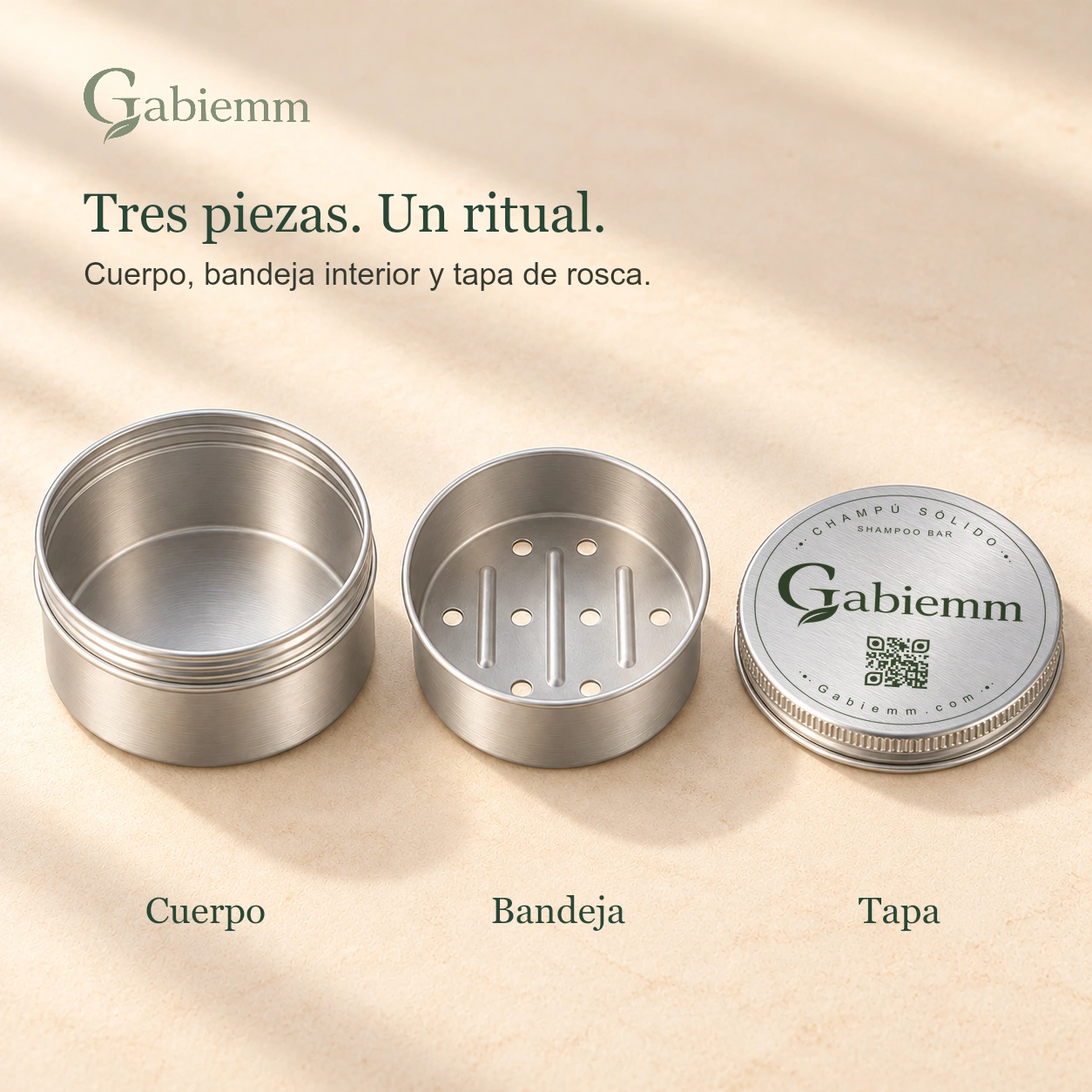 Composición digital de las tres piezas de la lata Gabiemm: cuerpo, bandeja interior con ocho orificios redondos y tres relieves, y tapa de rosca. Las tres piezas comparten acabado de aluminio satinado e iluminación cálida, con la impresión original de la tapa conservada.